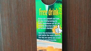 A hotel promotional item with a green and yellow design, featuring a 'Free drink' offer and a thumbs-up graphic.