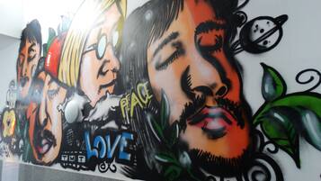 Eine Wand mit einem großen Wandbild, das Gesichter und die Wörter „PEACE LOVE“ zeigt.