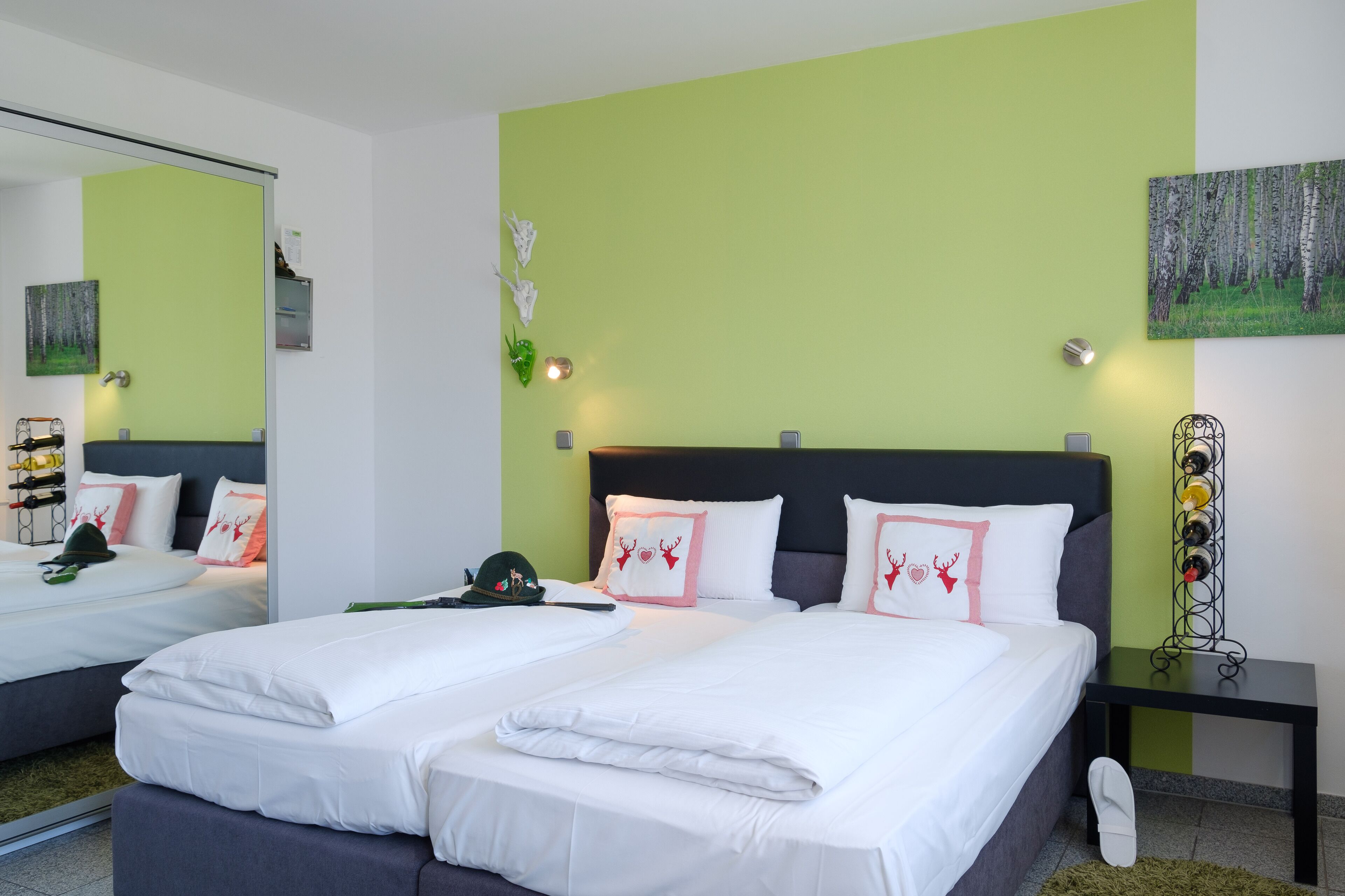 Ein Hotelzimmer mit zwei Betten, einem großen Spiegel, einem Gemälde und einem Weinkühlschrank.