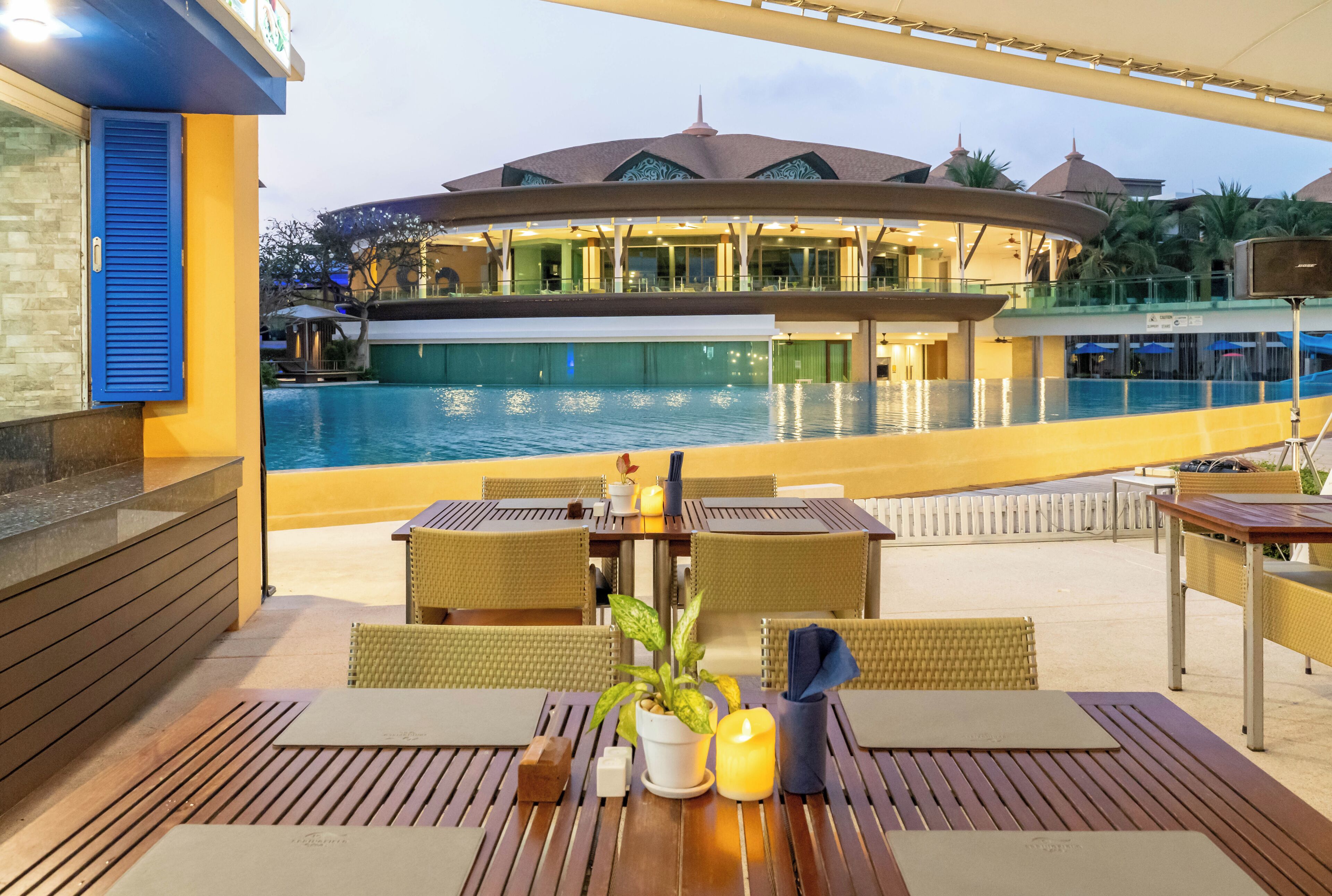 A poolside area with a dining table, chairs, and a potted plant.