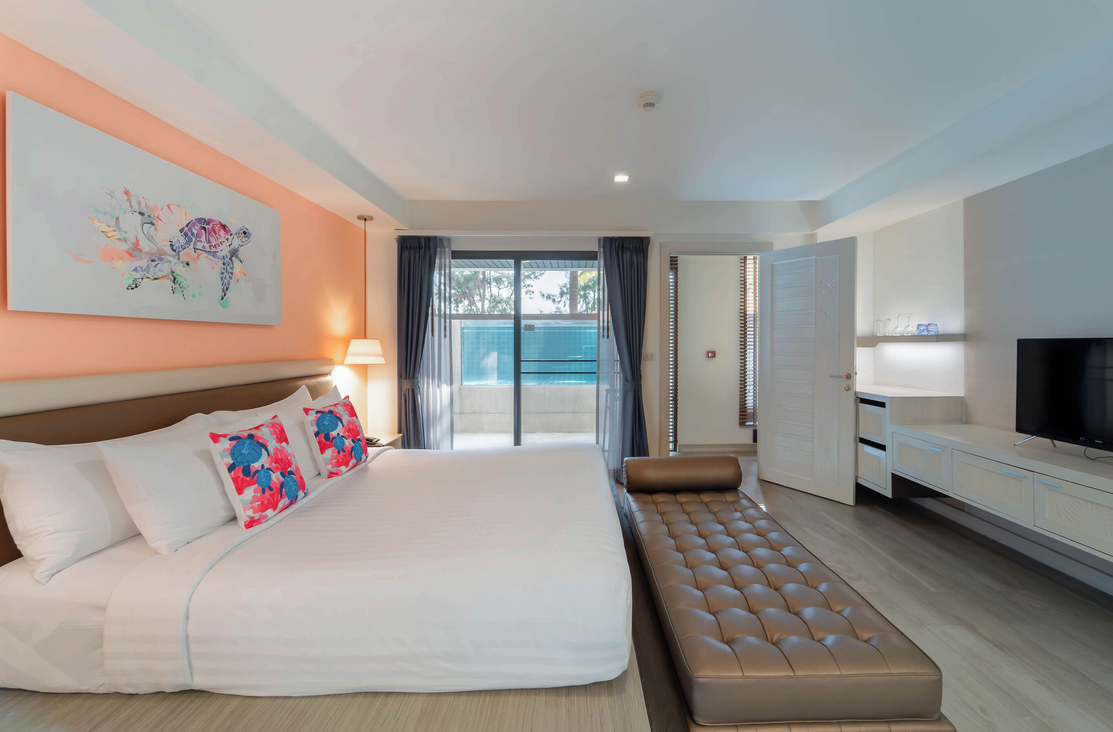 A modern hotel room with a large bed, a sofa, a TV, and a balcony with curtains.