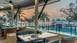 Un restaurant avec une terrasse, une vue sur la piscine et des palmiers.