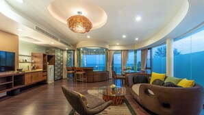 Un salon moderne comprenant un canapé, un fauteuil et une table basse, un coin cuisine et un balcon avec vue sur la mer.