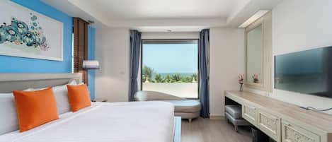 A hotel room with a large bed, a TV, a desk, and a view of the ocean.