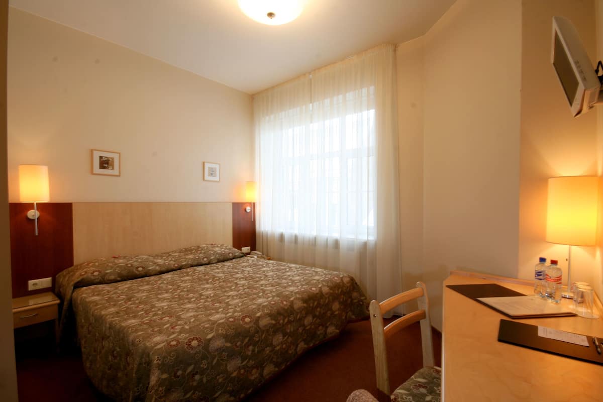 Une chambre d’hôtel avec deux lits, un bureau avec une chaise, une télévision et deux lampes.