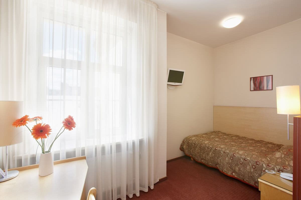 Une chambre d’hôtel avec un lit, un bureau doté d’une lampe, une télévision et un tableau accroché au mur.