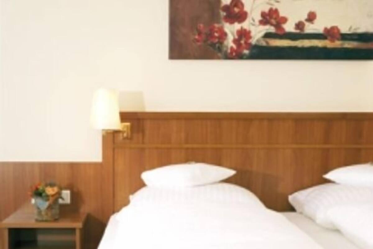 Une chambre d’hôtel avec un grand lit, une tête de lit en bois, une table de chevet avec une lampe et un tableau au mur.