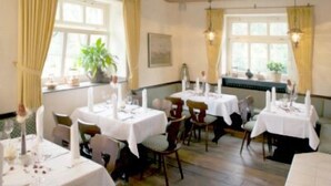 A dining area with multiple tables set for a meal, featuring white tablecloths and candles. - Waldhotel Nachtigall (Paderborn)