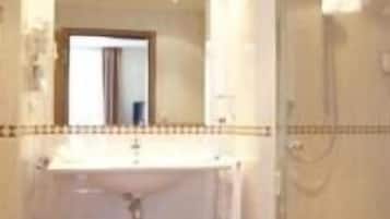 A bathroom with a sink, mirror, and shower.