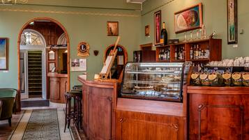 Een bar met houten kasten, een vitrine met gebak, en een groene wand met ingelijste foto's.