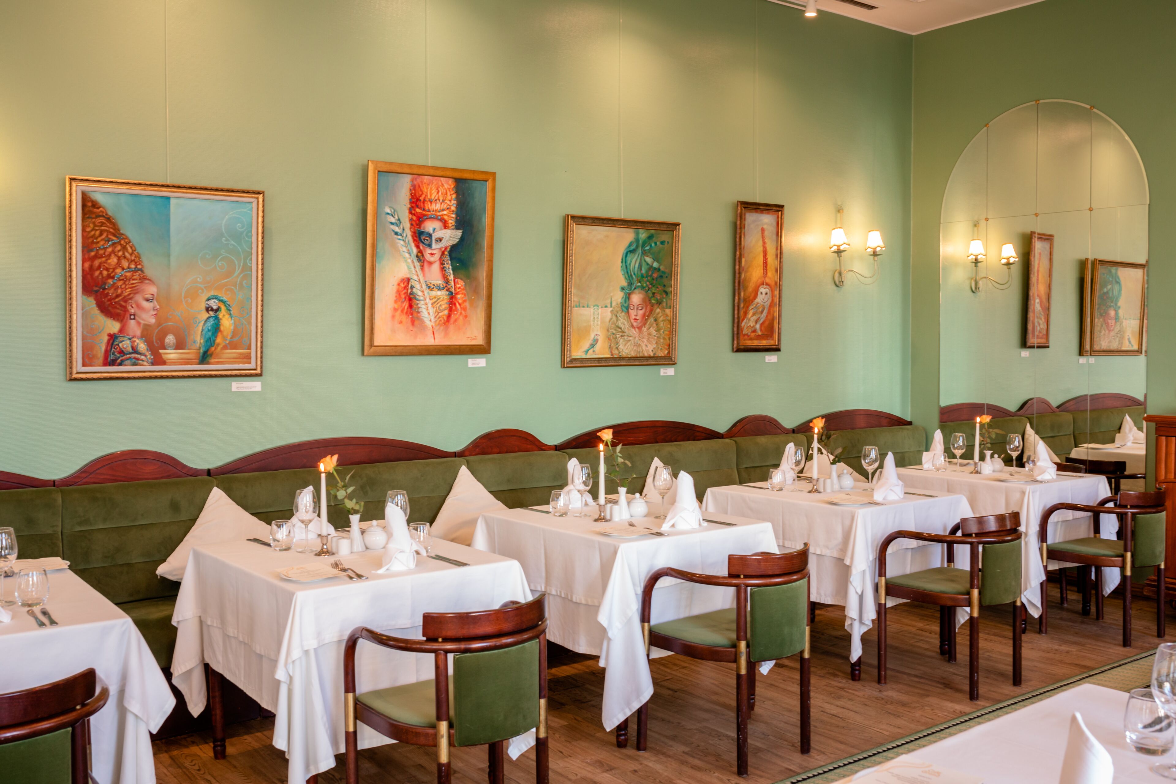 Un ristorante con panche rivestite in verde e tovagliati bianchi.