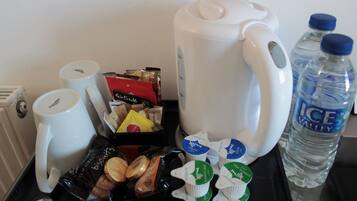 Una bandeja con cafetera, tazas, galletas, cartones de leche y una botella de agua.