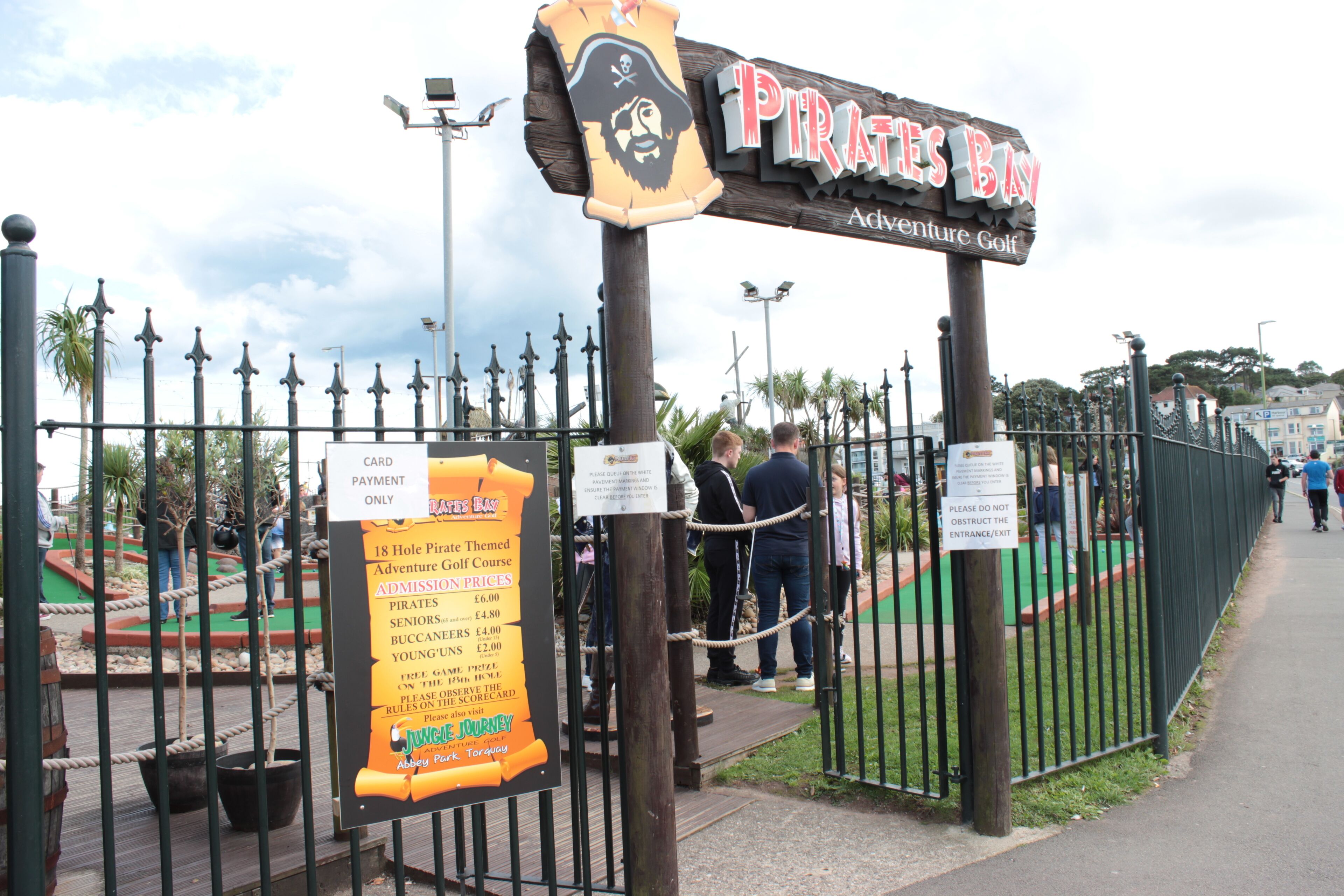 A sign for Pirates Bay Adventure Golf with admission prices listed.