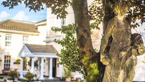 A statue of a woman and child in a garden setting with a building in the background. - Penventon Park Hotel (Redruth)