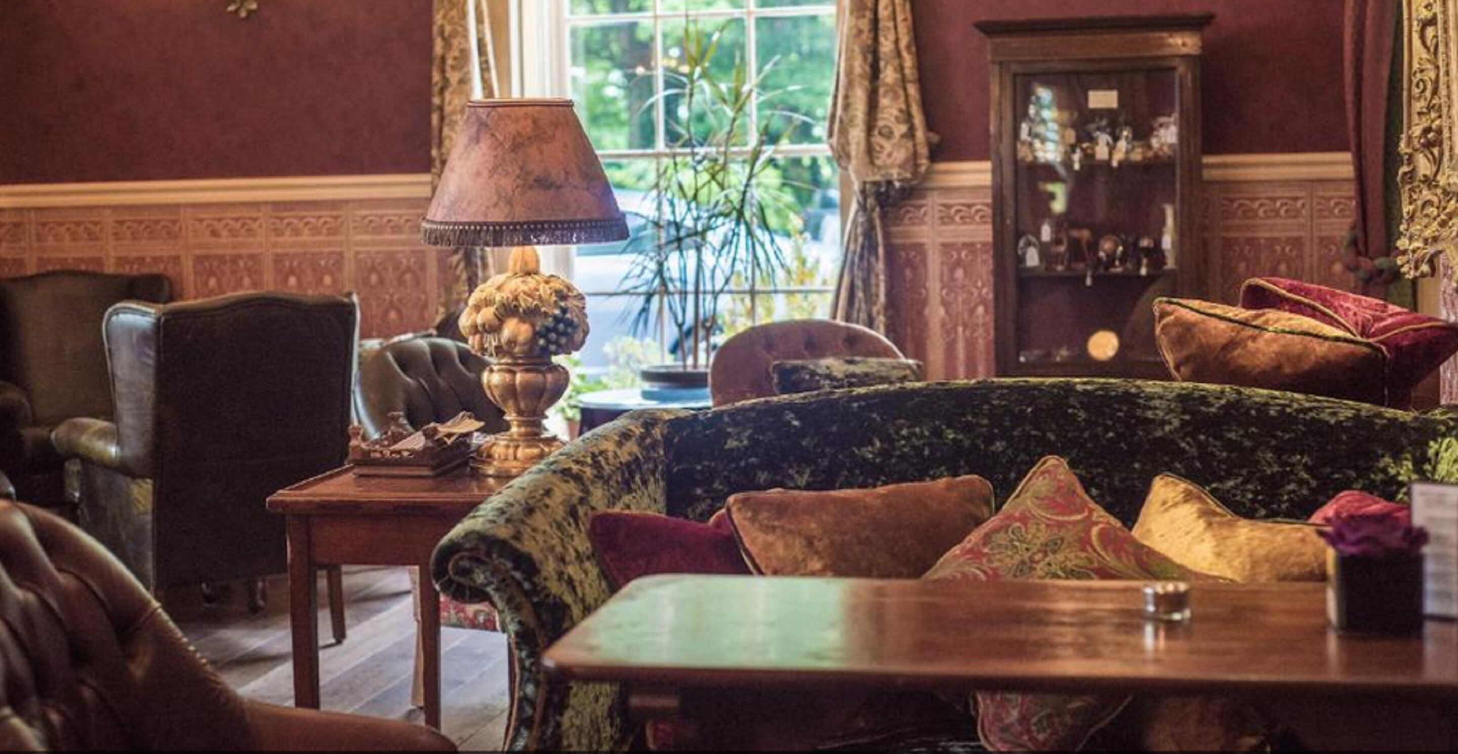 A traditional room with a patterned sofa, a wooden table, and a lamp.