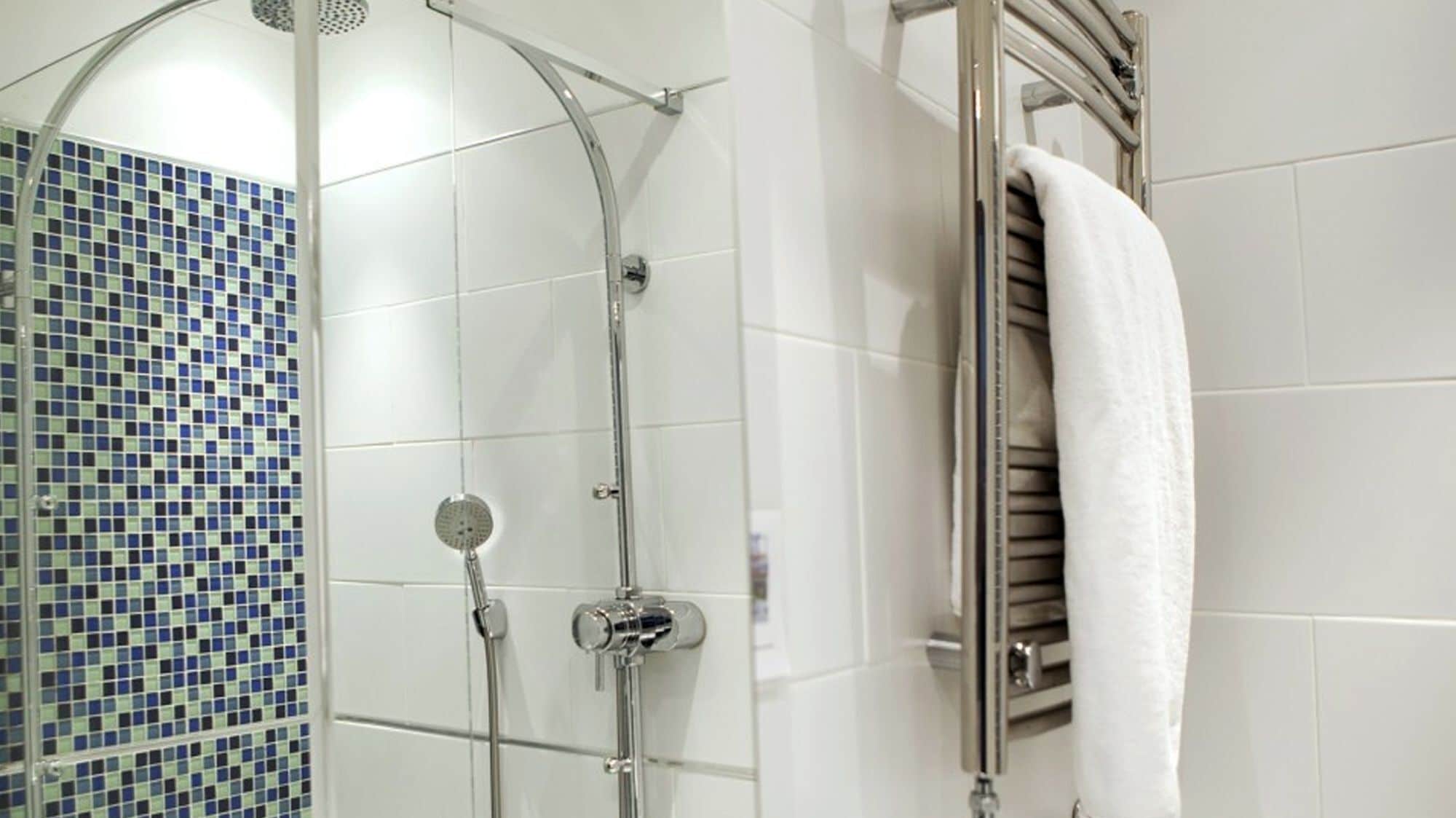 Een douche met een glazen deur en een betegelde wand.