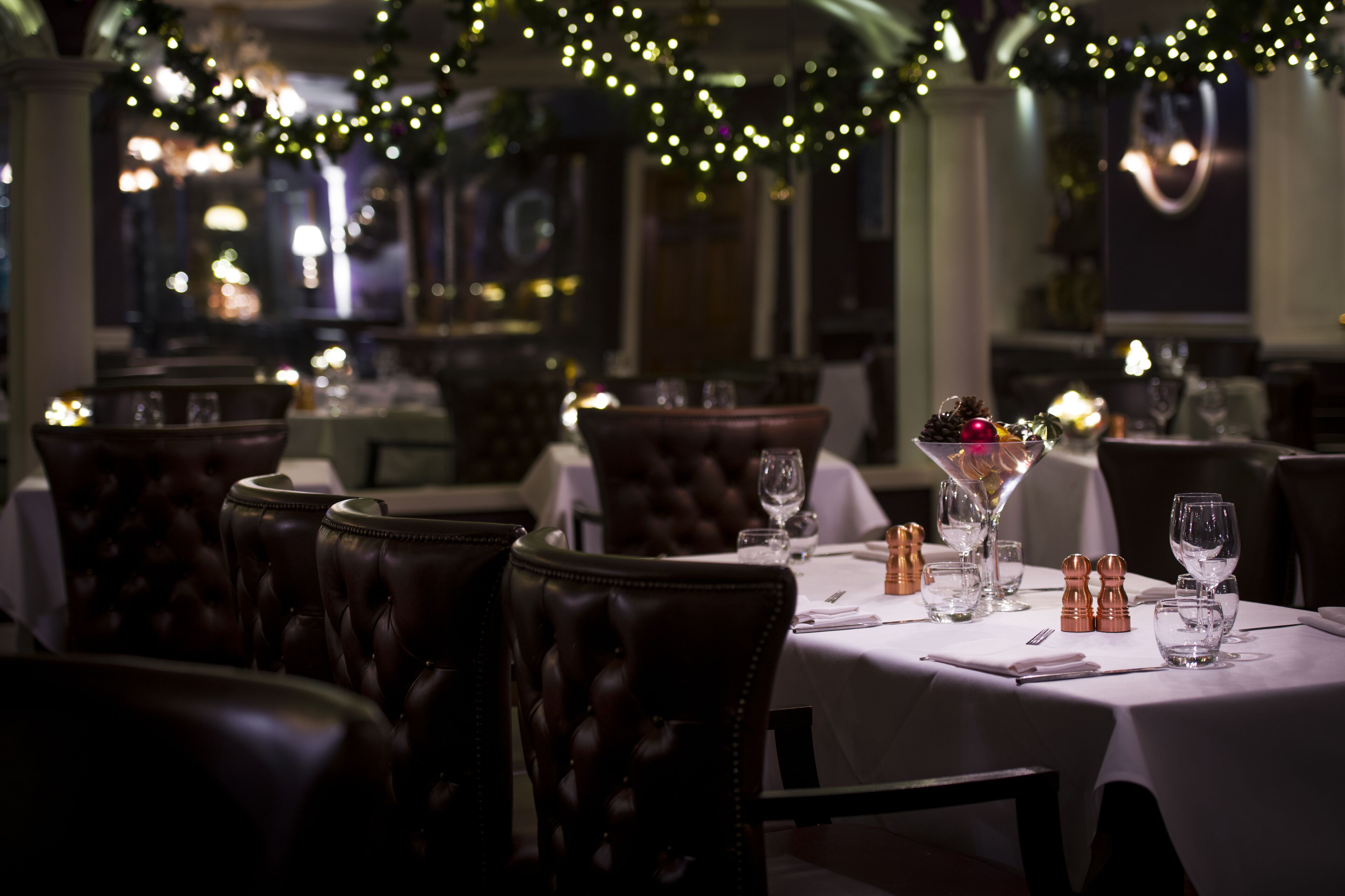 Un restaurante tenuemente iluminado con sillas y mesas de cuero dispuestas para comer.