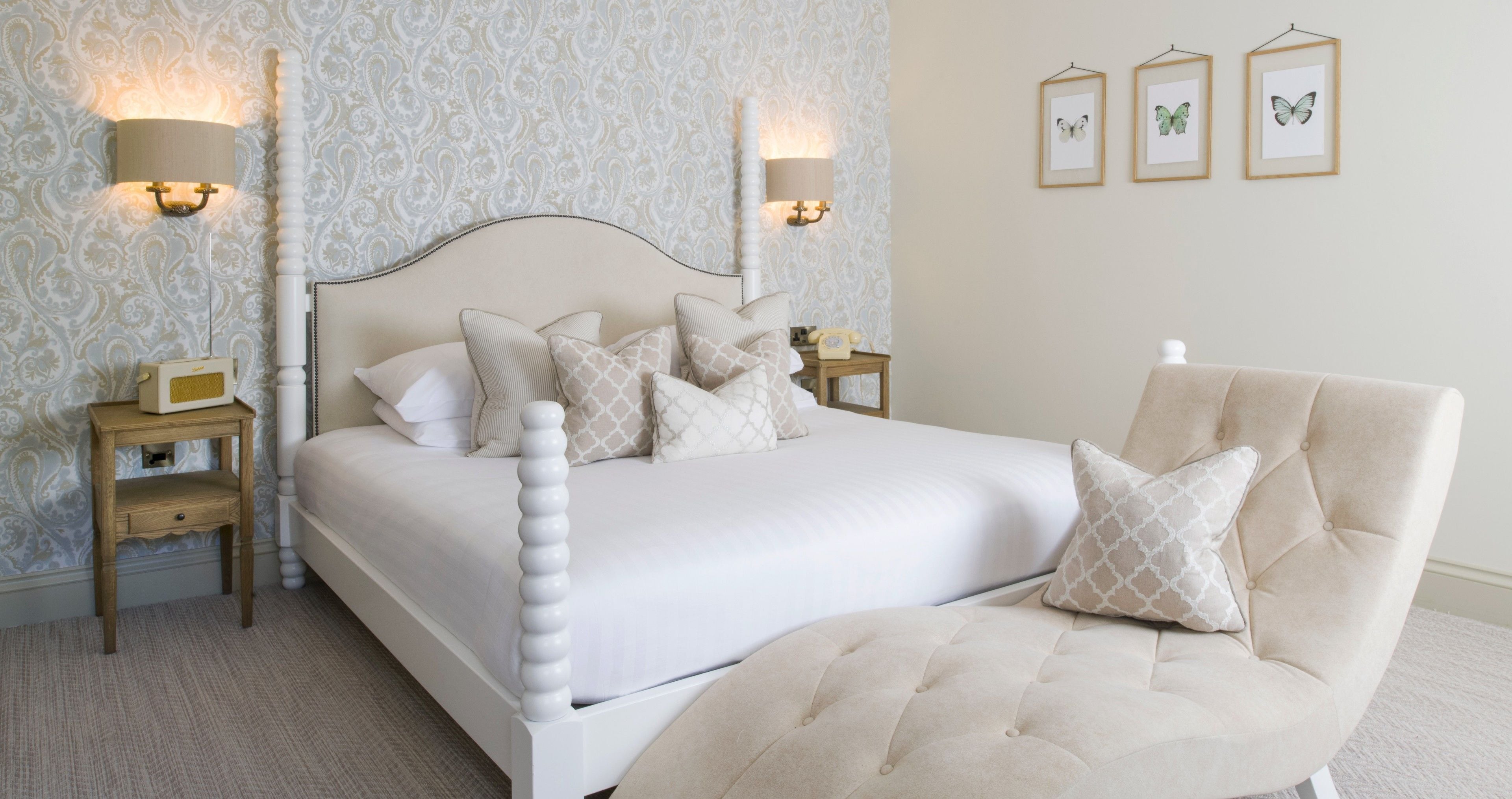 A bedroom with a large bed, two bedside tables, a chair, and wall-mounted lamps.