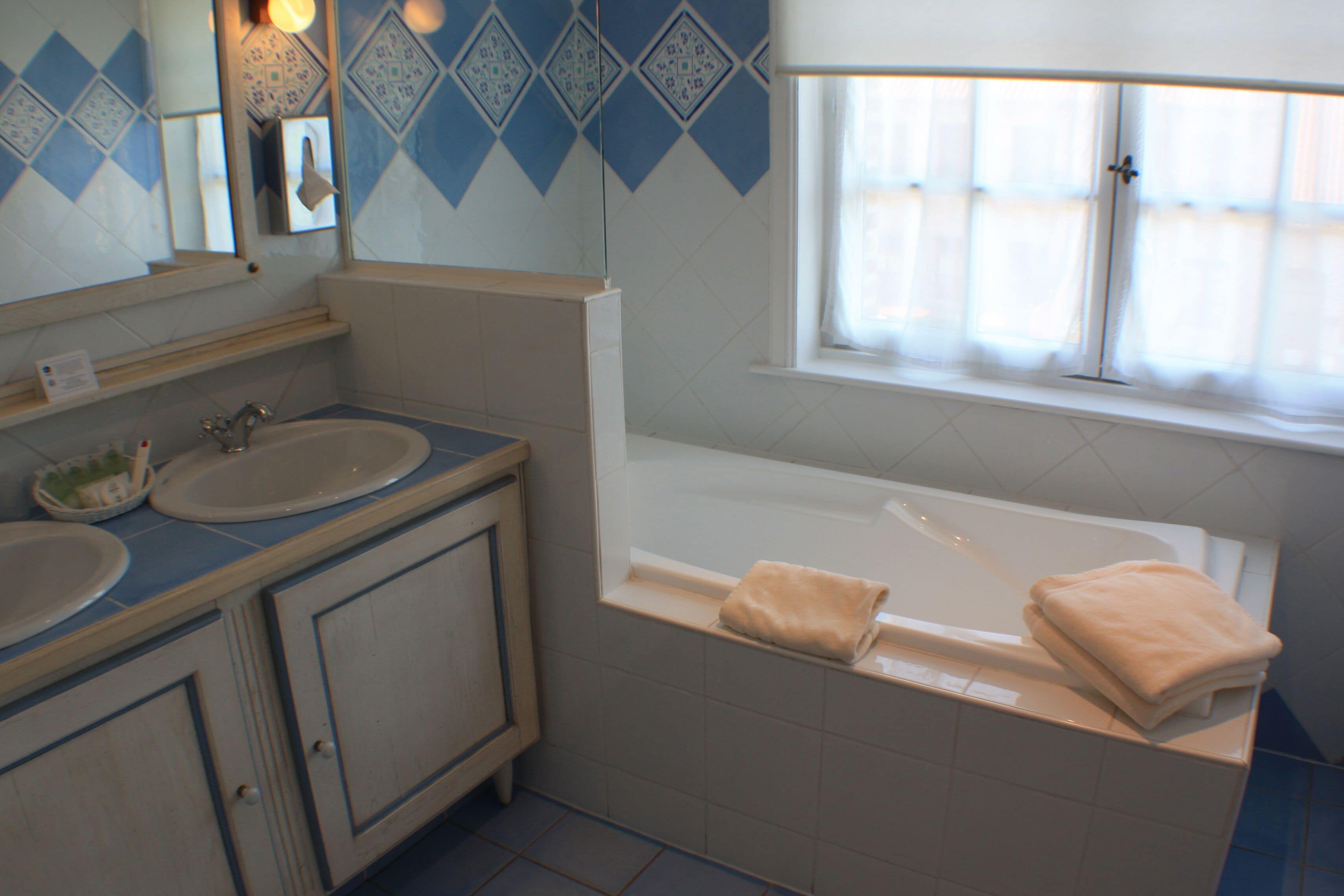 A bathroom with two sinks, a bathtub, and a window.