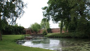 A serene riverside park with a brick wall and lush greenery.