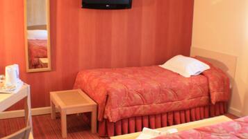 Een hotelkamer met een bed, een bureau met stoel, een aan de muur bevestigde televisie en een kleine tafel.