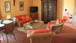A cozy living room with a sofa, armchairs, a coffee table, and a television.