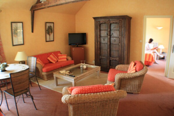Un salón acogedor con un sofá, sillones, una mesa de centro y un televisor.