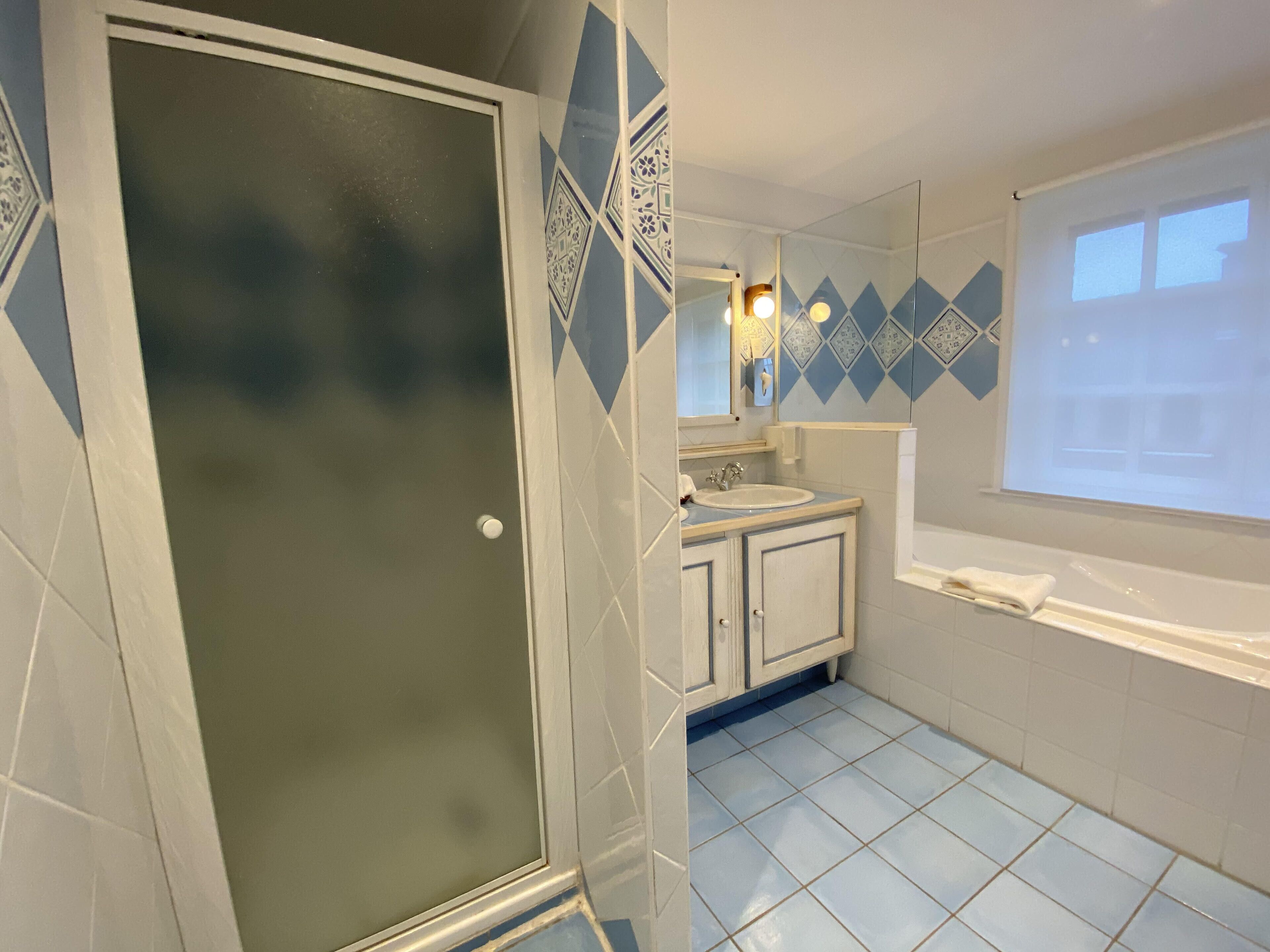 A bathroom with a shower, a sink, and a mirror.