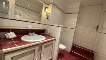 A bathroom with a white sink, a mirror, a toilet, and a door.