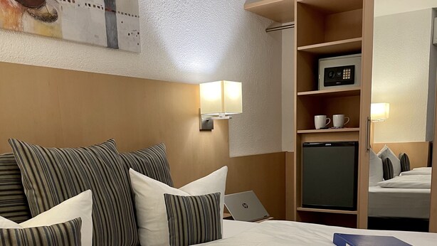 Hotelkamer met een groot bed, een bureau met een laptop, een minibar, een magnetron en een koffieapparaat.