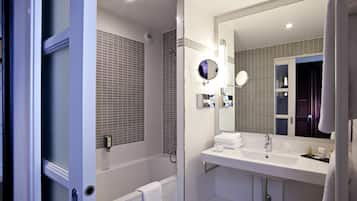 A modern bathroom with a walk-in shower, a large mirror, and a white sink.