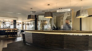 Un área de recepción moderna con mostrador, iluminación en el techo y un bar al fondo.