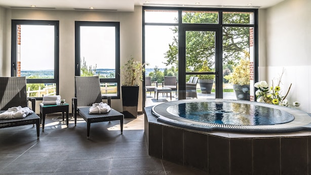 Área de piscina interior moderna con asientos y vistas al exterior.