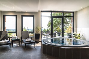 Ein moderner Innenpoolbereich mit Sitzgelegenheiten und Blick ins Freie.