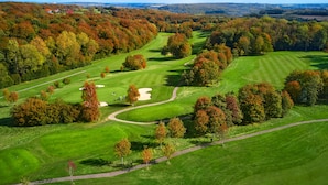 Un campo de golf con varios fairways, búnkeres de arena y un club house a lo lejos.