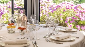 Una mesa preparada para una comida, con botellas de vino, copas y flores.