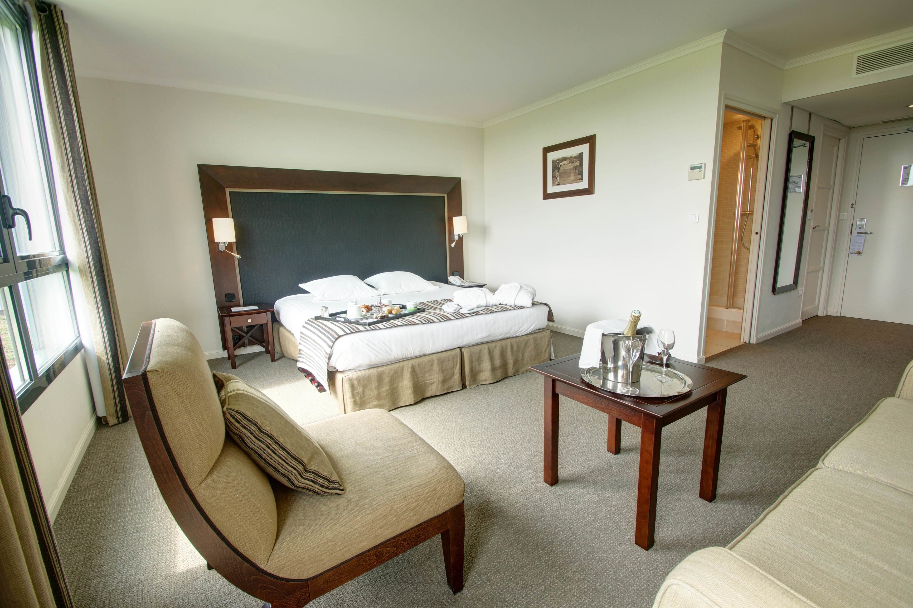 Camera d'albergo con un letto, una sedia, un tavolo con vassoio e una porta che dà sul bagno.