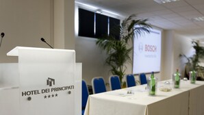 Une salle de conférence avec un pupitre portant l’inscription « HÔTEL DEI PRINCIPATI » et un écran affichant le mot « BOSCH ».