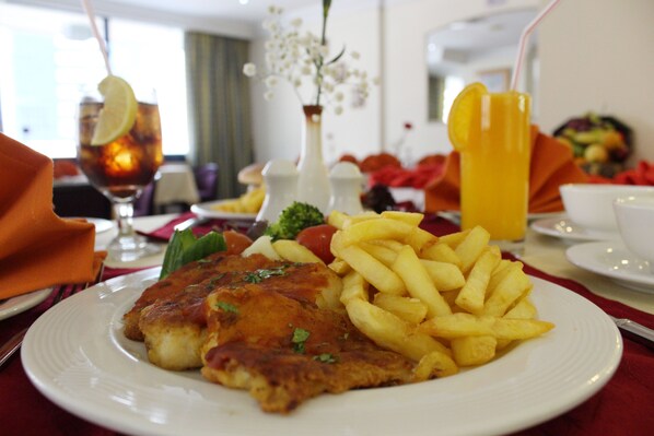 A plate of food with a fried item, fries, and a glass of orange juice. - Al Diar Mina (Abu Dhabi)