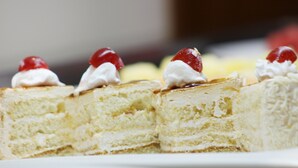 A slice of cake with whipped cream and cherries on top.