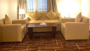 A hotel room with a sofa set, a coffee table, and a lamp.