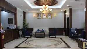 A lobby with a reception desk, seating area, and a chandelier.
