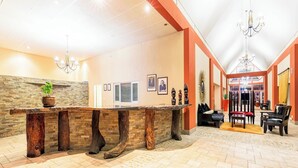 A reception area with a wooden reception desk, a chandelier, and a seating area with chairs and a table.