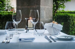Enjoy a romantic dinner amidst lush greenery and a serene stone structure.
