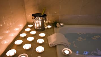 A spa area with a bathtub, candles, and a champagne bottle.