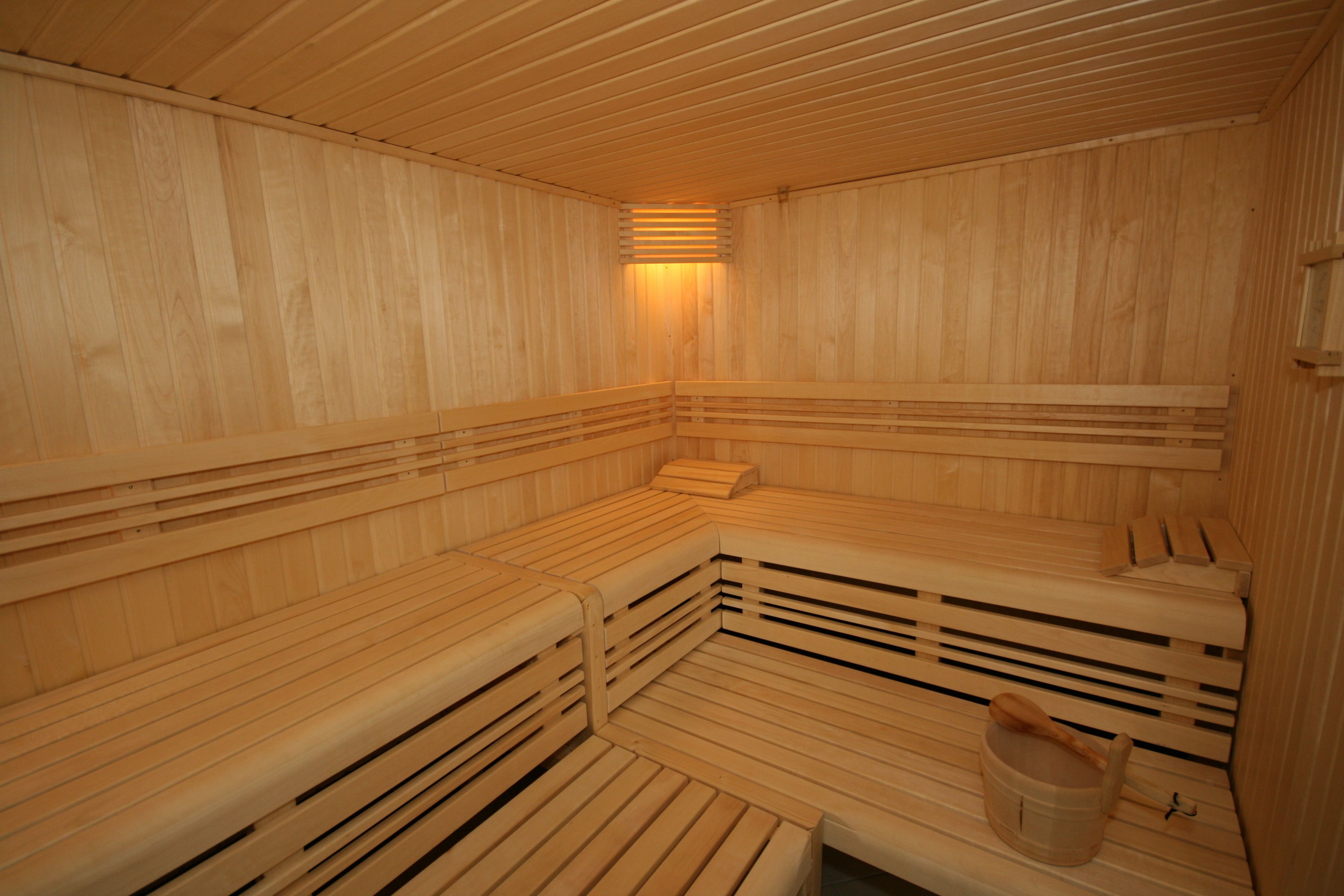 A sauna with wooden benches and a wooden bucket.