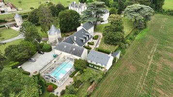 Vista aérea de una extensa propiedad con piscina, varias construcciones y abundante vegetación.