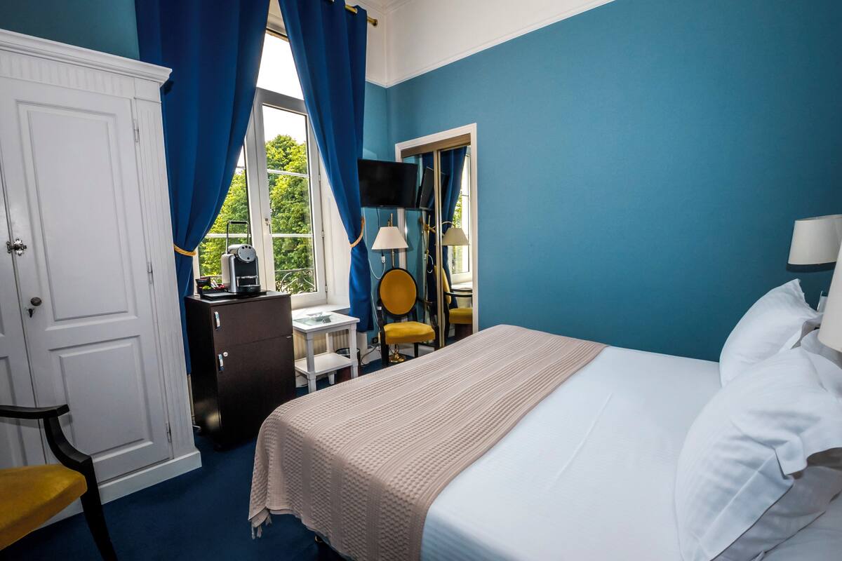 Hotellihuone, jossa on sänky, työpöytä, tuoli ja vaatekaappi.