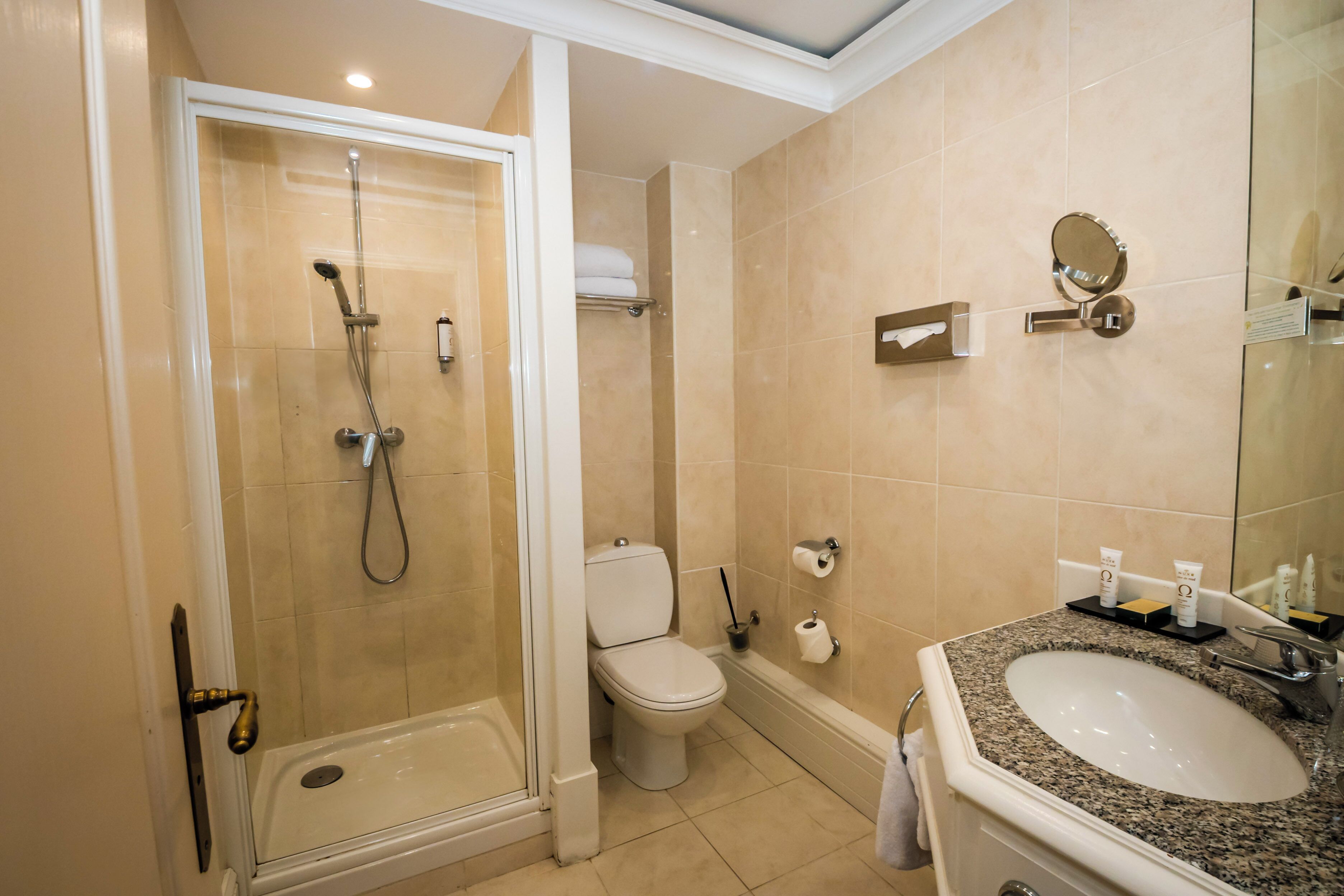 Une salle de bain équipée d’une douche, de toilettes, d’un lavabo et d’un miroir.