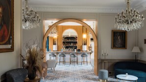 A spacious living area with a bar, a blue sofa, and a chandelier.